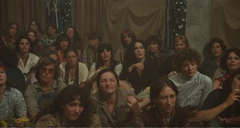 Movie still from “City of Women” (1980), directed by Federico Fellini – A group of people sitting in a room together; Medium shot, High angle