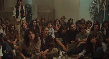 Movie still from “City of Women” (1980), directed by Federico Fellini – A large group of people sitting in a room together; Wide shot, High angle