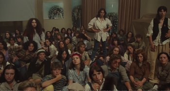 Movie still from “City of Women” (1980), directed by Federico Fellini – A large group of people sitting in a room; Wide shot, High angle