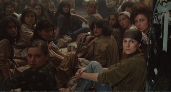Movie still from “City of Women” (1980), directed by Federico Fellini – A group of people sitting on the ground together; Medium shot, High angle