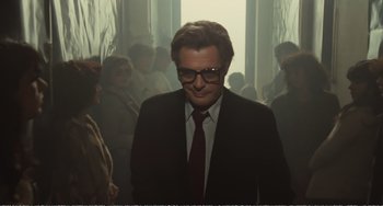 Movie still from “City of Women” (1980), directed by Federico Fellini – A man wearing a suit and tie standing in a room; Medium shot, Low angle