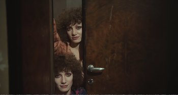 Movie still from “City of Women” (1980), directed by Federico Fellini – A woman with curly brown hair is standing in front of a mirror; Close Up shot, High angle