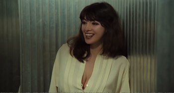 Movie still from “City of Women” (1980), directed by Federico Fellini – A woman in a white shirt smiling for the camera; Close Up shot, High angle