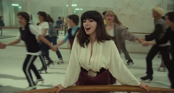 Movie still from “City of Women” (1980), directed by Federico Fellini – A woman in white shirt and red skirt sitting on a bench; Medium shot, High angle