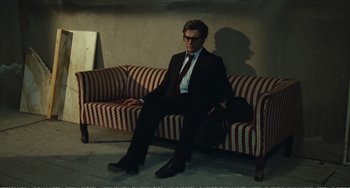 Movie still from “City of Women” (1980), directed by Federico Fellini – A man sitting on a couch in a room; Wide shot, High angle