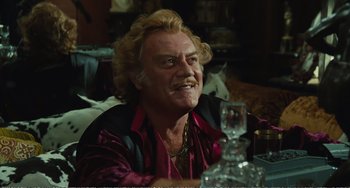 Movie still from “City of Women” (1980), directed by Federico Fellini – A person sitting at a table; Close Up shot, Low angle