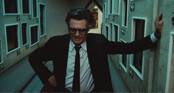 Movie still from “City of Women” (1980), directed by Federico Fellini – A man wearing a suit and tie standing in a hallway; Medium shot, Low angle