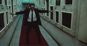 Movie still from “City of Women” (1980), directed by Federico Fellini – A man wearing a suit and tie standing on a red carpet; Wide shot, Low angle