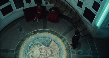 Movie still from “City of Women” (1980), directed by Federico Fellini – Two people sitting on a couch in a room with a mosaic floor; Extreme Wide shot, Overhead angle