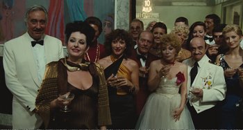 Movie still from “City of Women” (1980), directed by Federico Fellini – A group of people standing next to each other holding wine glasses; Wide shot, High angle