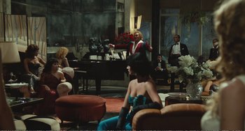Movie still from “City of Women” (1980), directed by Federico Fellini – A group of people sitting in a living room; Wide shot, Over the shoulder angle