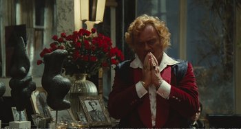 Movie still from “City of Women” (1980), directed by Federico Fellini – An older woman is praying in front of a vase of roses; Medium shot, Over the shoulder angle