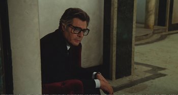 Movie still from “City of Women” (1980), directed by Federico Fellini – A man sitting down wearing a suit and glasses; Medium shot, Over the shoulder angle
