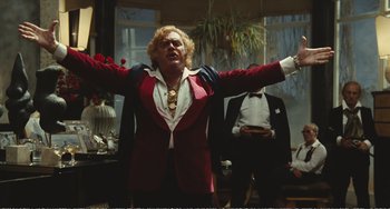 Movie still from “City of Women” (1980), directed by Federico Fellini – A man in a red jacket is raising his arms; Medium shot, Low angle