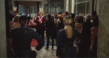Movie still from “City of Women” (1980), directed by Federico Fellini – A group of people standing in a room; Wide shot, Over the shoulder angle