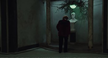 Movie still from “City of Women” (1980), directed by Federico Fellini – A man standing in front of a statue in a dark room; Wide shot, Over the shoulder angle