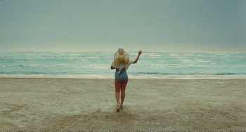 Movie still from “City of Women” (1980), directed by Federico Fellini – A woman walking on the beach holding a frisbee; Extreme Wide shot, High angle