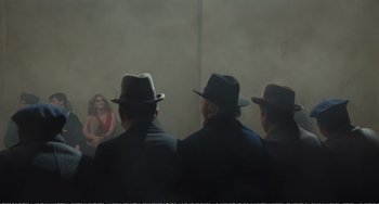 Movie still from “City of Women” (1980), directed by Federico Fellini – A group of men sitting next to each other wearing hats; Wide shot, Over the shoulder angle