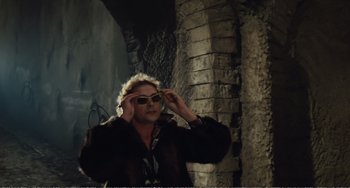 Movie still from “City of Women” (1980), directed by Federico Fellini – A woman wearing sunglasses standing in front of a stone wall; Medium shot, Low angle