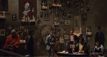 Movie still from “City of Women” (1980), directed by Federico Fellini – A group of people sitting in a room with candles; Wide shot, High angle