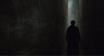 Movie still from “City of Women” (1980), directed by Federico Fellini – A man standing in front of a wall with smoke coming out of it; Wide shot, High angle