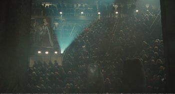 Movie still from “City of Women” (1980), directed by Federico Fellini – A crowd of people standing in front of a stage; Extreme Wide shot, High angle