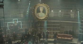 Movie still from “City of Women” (1980), directed by Federico Fellini – A crowd of people standing in a room with a painting hanging on the wall; Extreme Wide shot, High angle