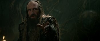 Movie still from “Clash of the Titans” (2010), directed by Louis Leterrier – A man with long hair and a long beard is holding something; Close Up shot, Over the shoulder angle