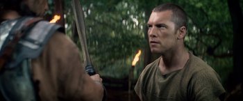 Movie still from “Clash of the Titans” (2010), directed by Louis Leterrier – A man holding a bow and arrow in the woods; Close Up shot, Over the shoulder angle