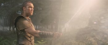 Movie still from “Clash of the Titans” (2010), directed by Louis Leterrier – A man holding a bow and arrow in the woods; Medium shot, Low angle