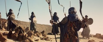 Movie still from “Clash of the Titans” (2010), directed by Louis Leterrier – A group of people dressed in costume walking in the desert; Wide shot, Low angle