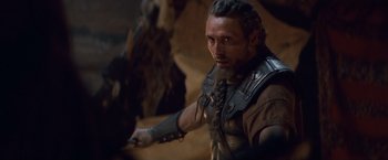 Movie still from “Clash of the Titans” (2010), directed by Louis Leterrier – A man with a long beard and a leather vest; Close Up shot, Over the shoulder angle