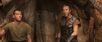 Movie still from “Clash of the Titans” (2010), directed by Louis Leterrier – A man with a beard is standing in front of a wall; Medium shot, Over the shoulder angle