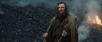 Movie still from “Clash of the Titans” (2010), directed by Louis Leterrier – A man with long hair and a long beard holding a stick; Medium shot, Low angle