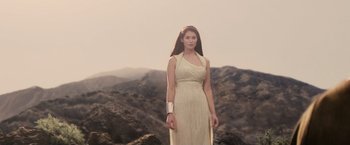 Movie still from “Clash of the Titans” (2010), directed by Louis Leterrier – A woman standing on top of a hill wearing a white dress; Medium shot, Low angle
