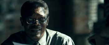 Movie still from “Cleaner” (2007), directed by Renny Harlin – An older man wearing glasses and a tie; Close Up shot, Over the shoulder angle