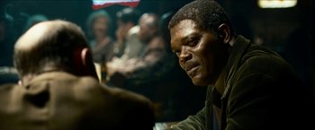 Movie still from “Cleaner” (2007), directed by Renny Harlin – A person sitting at a table in front of other people; Close Up shot, Over the shoulder angle