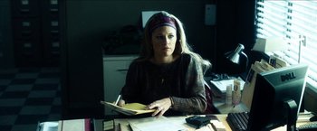 Movie still from “Cleaner” (2007), directed by Renny Harlin – A woman sitting at a table with a notebook; Medium shot, Over the shoulder angle