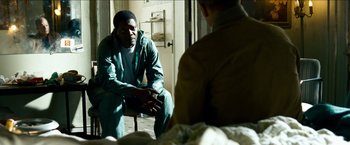 Movie still from “Cleaner” (2007), directed by Renny Harlin – A man sitting on a chair in a room with another man; Medium shot, Over the shoulder angle