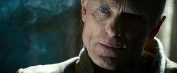 Movie still from “Cleaner” (2007), directed by Renny Harlin – An older man with a blue eye stares at the camera; Close Up shot, Over the shoulder angle