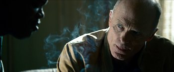 Movie still from “Cleaner” (2007), directed by Renny Harlin – An older man is smoking a cigarette and looking at the camera; Close Up shot, Low angle