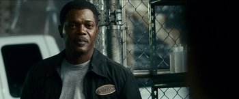 Movie still from “Cleaner” (2007), directed by Renny Harlin – A man standing in front of a chain link fence; Close Up shot, Low angle