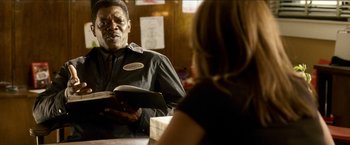 Movie still from “Cleaner” (2007), directed by Renny Harlin – A man holding a book in front of a woman; Close Up shot, Over the shoulder angle