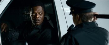Movie still from “Cleaner” (2007), directed by Renny Harlin – A man sitting in the back of a car next to a police officer; Close Up shot, Over the shoulder angle