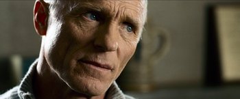 Movie still from “Cleaner” (2007), directed by Renny Harlin – An older man with blue eyes stares into the camera; Close Up shot, Over the shoulder angle