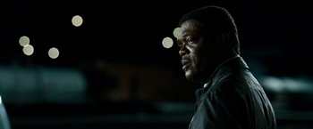 Movie still from “Cleaner” (2007), directed by Renny Harlin – A man standing in front of a building at night; Close Up shot, Over the shoulder angle