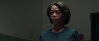 A woman in a green dress is looking at the camera
