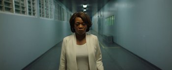 A woman in a white jacket standing in a hallway