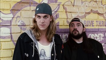 Movie still from “Clerks II” (2006), directed by Kevin Smith – A man and a woman standing next to each other in front of a brick wall; Medium shot, Low angle