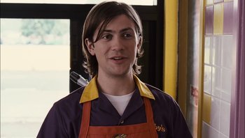 Movie still from “Clerks II” (2006), directed by Kevin Smith – A young man wearing an orange apron and purple shirt; Close Up shot, Over the shoulder angle